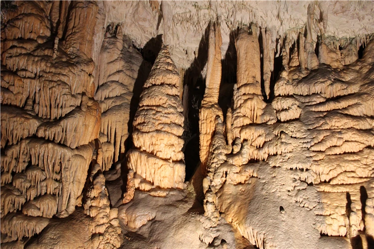 Stalaktity a stalagmity v osvětlené jeskyni s vápencovými útvary | Slovinsko křížem krážem