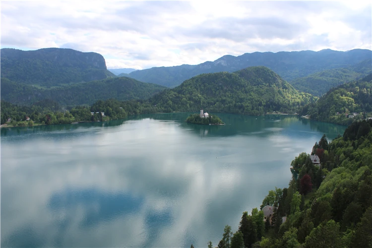 Pohled naBledské jezero s ostrůvkem a kostelem, obklopené zalesněnými horami, Slovinsko. | Slovinsko křížem krážem