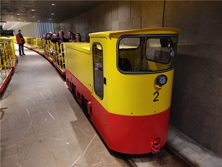 Žluto-červená důlní vláčková lokomotiva s turisty v podzemním tunelu | Slovinsko křížem krážem