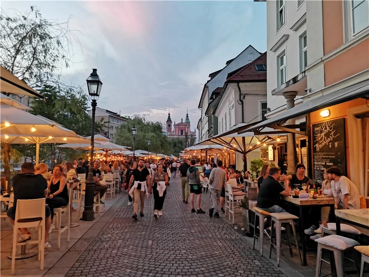 Rušná večerní promenáda v Lublani s restauracemi a výhledem na růžový kostel. | Slovinsko křížem krážem