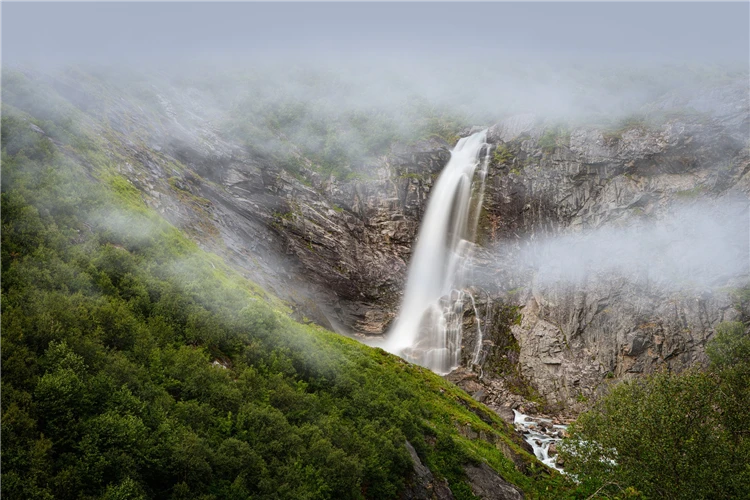 Vysoký norský vodopád padající do fjordu v zelené krajině | Ztraceni mezi fjordy – okruh Skandinávií
