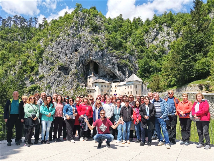 Skupina turistů před Predámským hradem vestavěným do skály, Slovinsko | Slovinsko křížem krážem