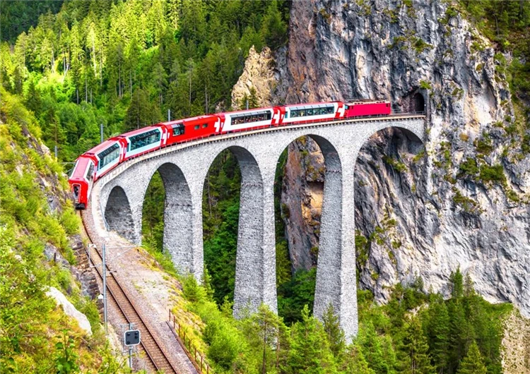 Bernina Express projíždí zasněženou alpskou krajinou ve Švýcarsku | Švýcarsko letecky s panoramatickými vlaky Bernina Express a Ledovcový Express